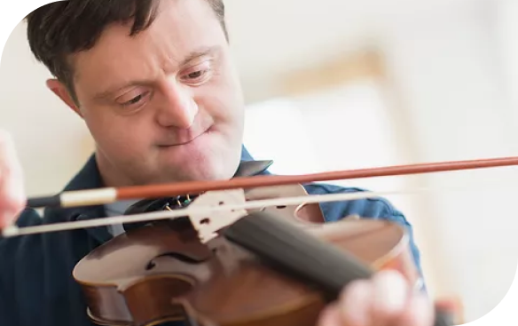 A man with Down syndrome in a blue shirt is focused on playing a violin with a bow.