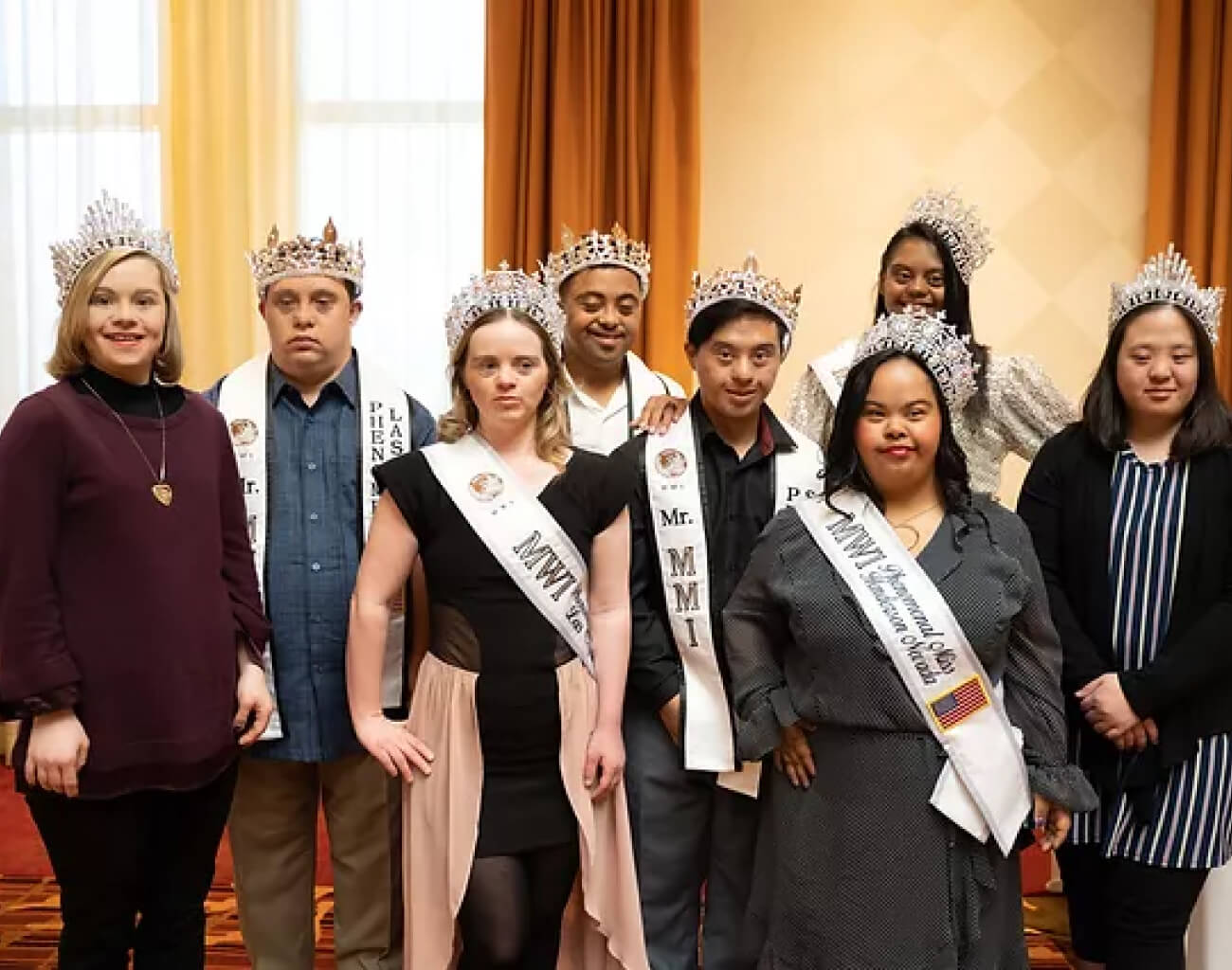 Nine people wearing crowns and sashes, some with "MWI Phenomenal Miss Henderson Nevada" printed on them.