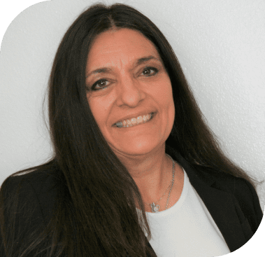 A smiling woman with long dark hair, wearing a black blazer and white shirt, looks directly forward.