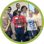 Seven smiling people pose for a group photo; one wears a red shirt with "JUST GIVING" on it.